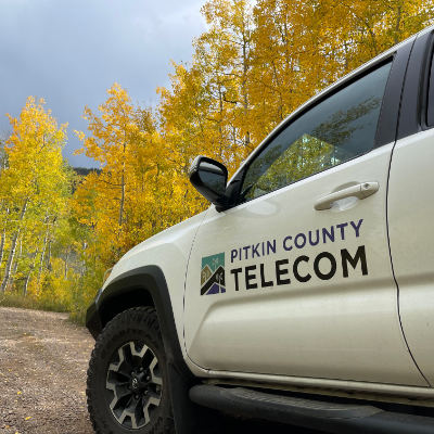 Camión de telecomunicaciones con álamos temblones en otoño